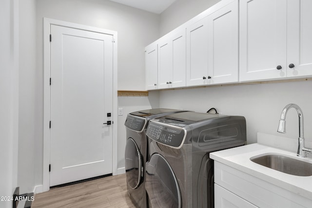 laundry room featuring light wood-type flooring, washing machine and dryer, cabinet space, and a sink