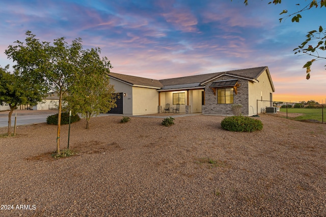 mid-century home featuring brick siding, stucco siding, an attached garage, fence, and cooling unit