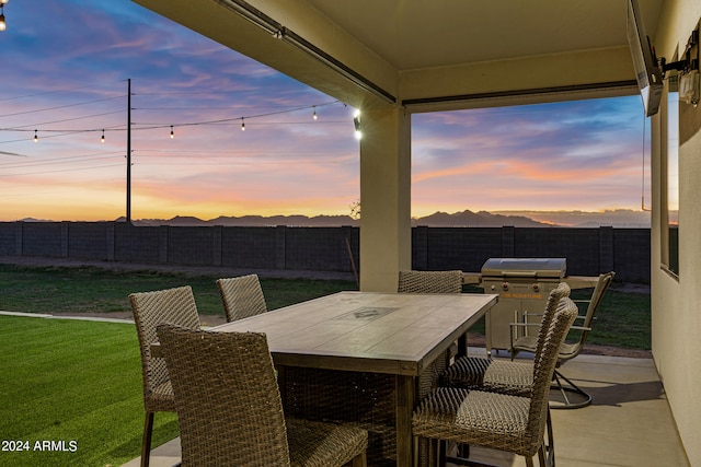 patio terrace at dusk with a yard and a grill