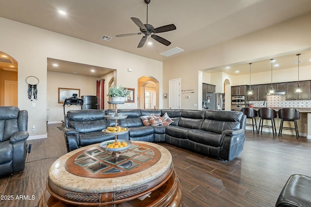 living room with arched walkways, recessed lighting, visible vents, dark wood-type flooring, and a ceiling fan