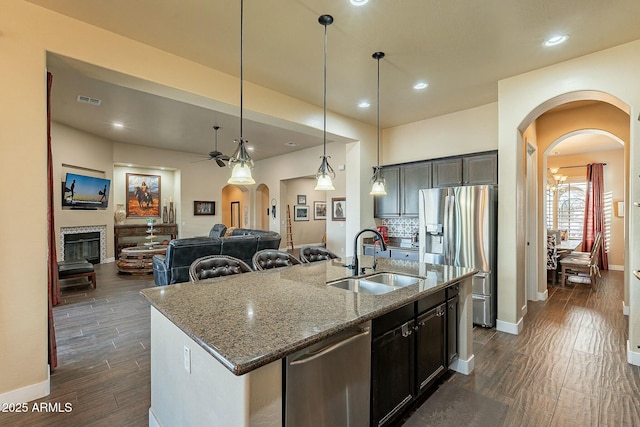 kitchen with arched walkways, stainless steel appliances, a sink, and open floor plan