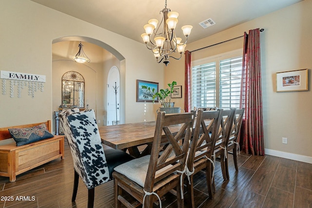 dining room with baseboards, visible vents, dark wood finished floors, arched walkways, and a chandelier