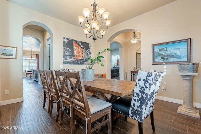 dining room featuring baseboards, arched walkways, a notable chandelier, and wood finished floors