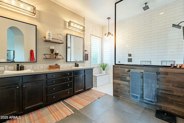 bathroom featuring tile patterned flooring, a walk in shower, tile walls, and double vanity