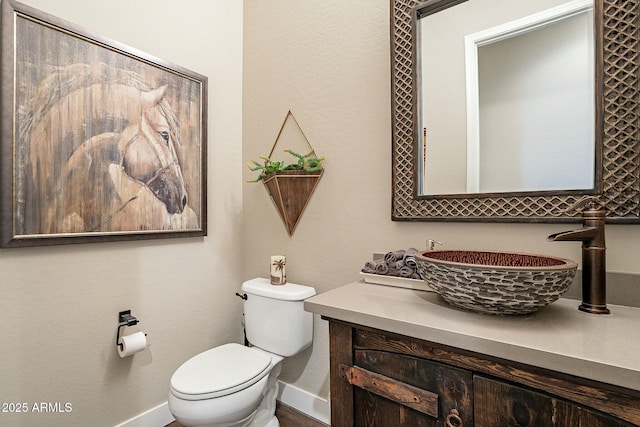 bathroom with toilet, vanity, and baseboards