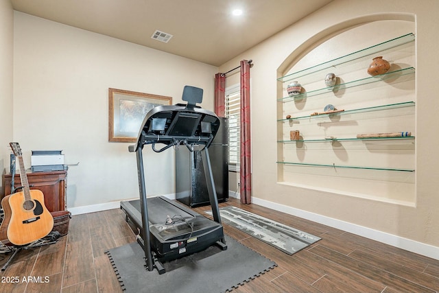 exercise area with wood finished floors, visible vents, and baseboards