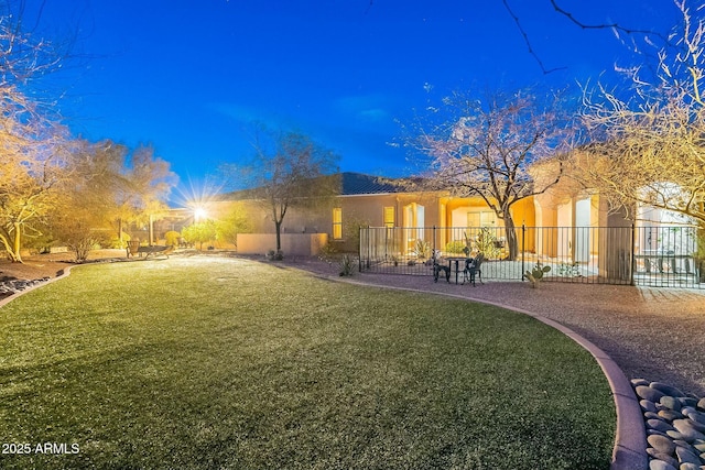 back of property with a lawn, a tile roof, fence, and stucco siding