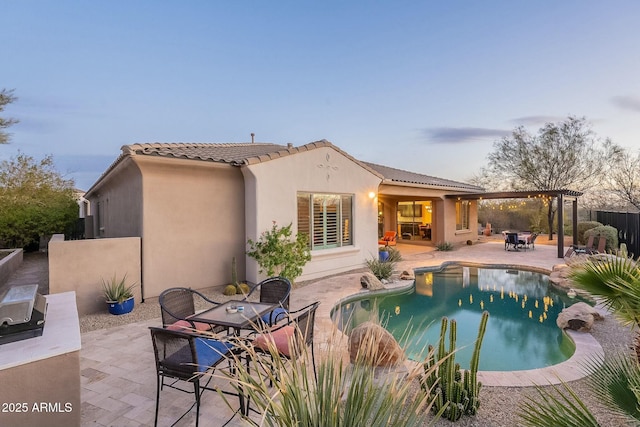 rear view of property featuring a patio, a tiled roof, a fenced in pool, stucco siding, and outdoor dining space