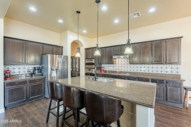 kitchen featuring wood finish floors, visible vents, appliances with stainless steel finishes, a sink, and dark brown cabinets