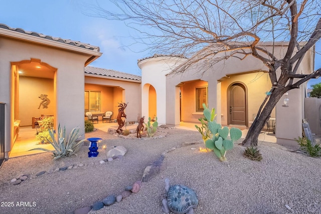 exterior space with a patio area, a tile roof, and stucco siding