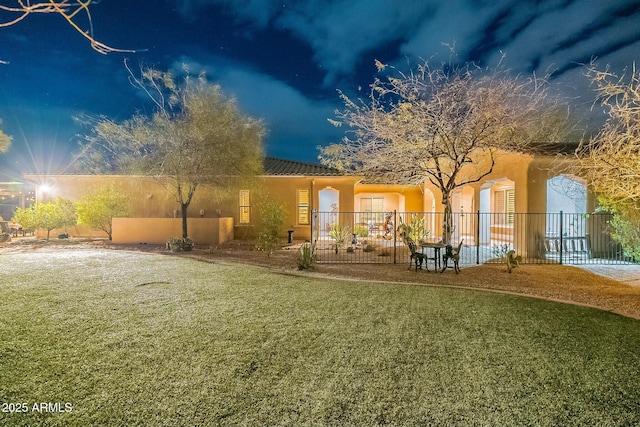 back of property featuring a yard, fence, and stucco siding