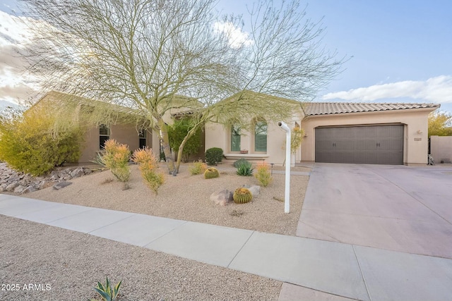 view of front of house with an attached garage, a tile roof, concrete driveway, and stucco siding