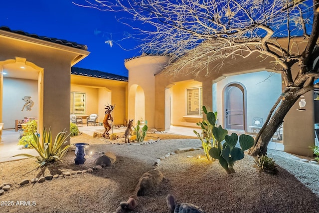 exterior space featuring a patio, a tile roof, and stucco siding