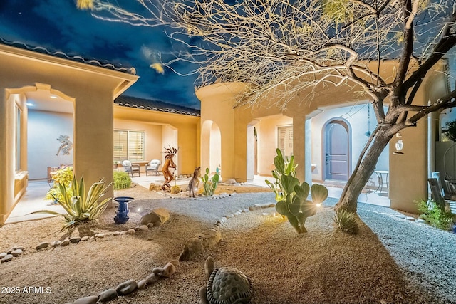 exterior space featuring a patio area, a tile roof, and stucco siding