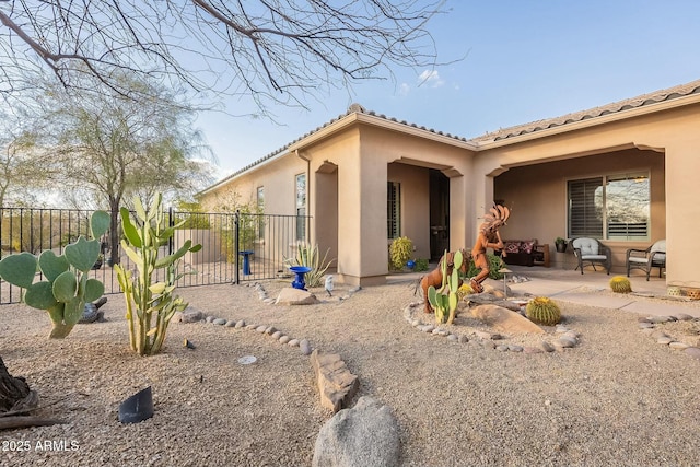 rear view of property with a tiled roof, stucco siding, a patio area, fence, and an outdoor living space