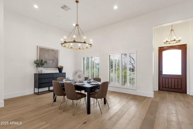 dining area with a healthy amount of sunlight, light wood-type flooring, and a notable chandelier