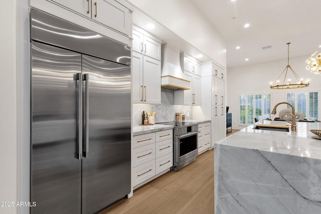 kitchen featuring white cabinetry, stainless steel appliances, light stone countertops, and sink