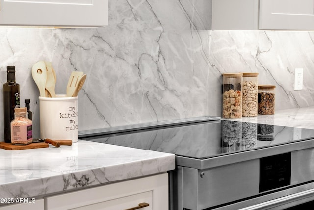 kitchen featuring light stone countertops, white cabinets, and electric range