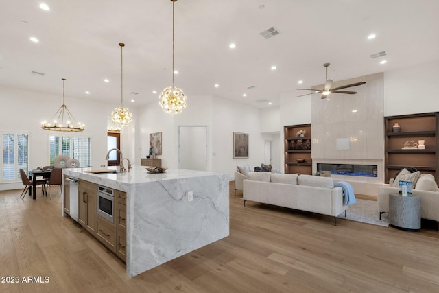 kitchen featuring sink, light stone counters, hanging light fixtures, a large island, and a high ceiling