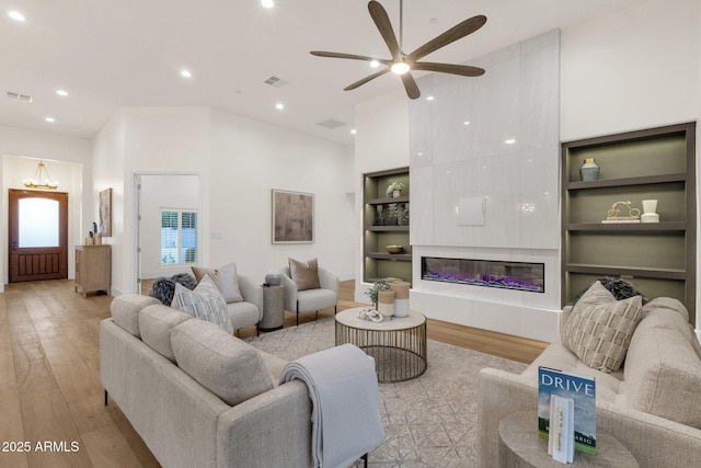 living room featuring ceiling fan, high vaulted ceiling, light hardwood / wood-style floors, and built in features