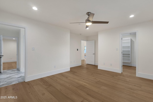 unfurnished bedroom with a spacious closet, ceiling fan, and light hardwood / wood-style flooring