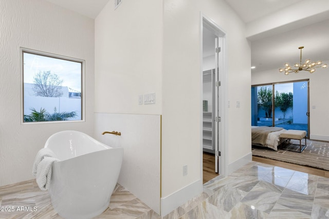 bathroom with a washtub and a chandelier