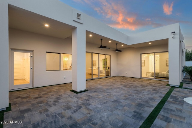 back house at dusk featuring ceiling fan and a patio area