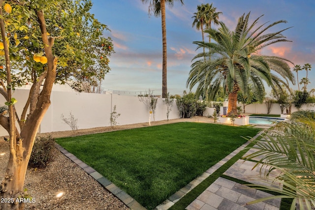 yard at dusk with a fenced in pool and a patio area