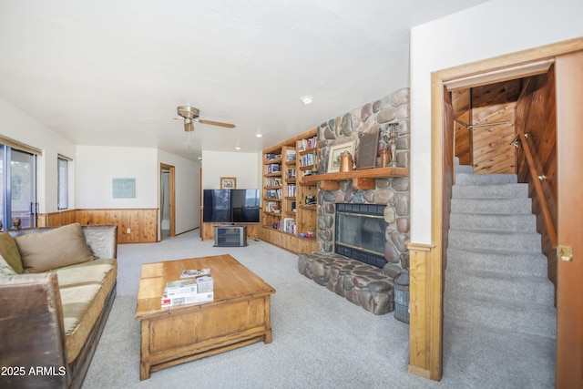 125 Partridge Ln, Prescott, AZ 86303 - carpeted living room featuring a ceiling fan, a fireplace, wooden walls, stairway, and wainscoting