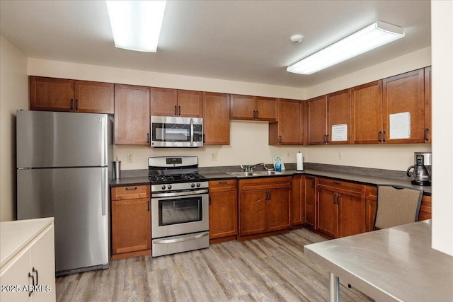 125 Partridge Ln, Prescott, AZ 86303 - kitchen with brown cabinetry, light wood-type flooring, dark countertops, a sink, and stainless steel appliances