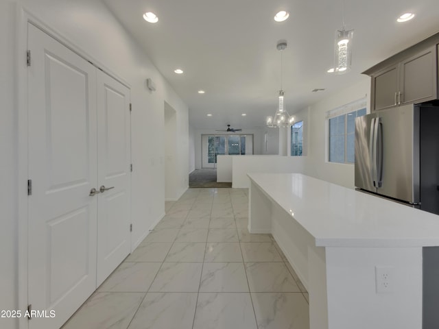 kitchen with recessed lighting, a kitchen island, marble finish floor, and light countertops