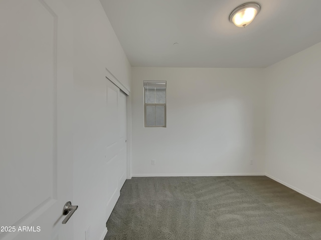 empty room with baseboards and dark colored carpet