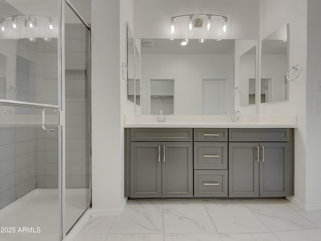 full bathroom with double vanity, marble finish floor, a stall shower, and a sink