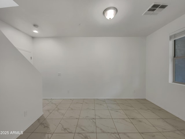 empty room featuring visible vents, baseboards, and marble finish floor