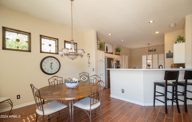 dining space with dark hardwood / wood-style flooring and an inviting chandelier