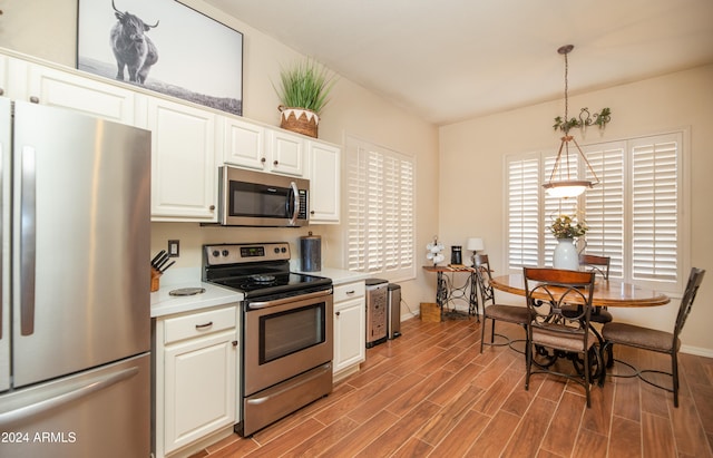 kitchen with hanging light fixtures, appliances with stainless steel finishes, and white cabinets