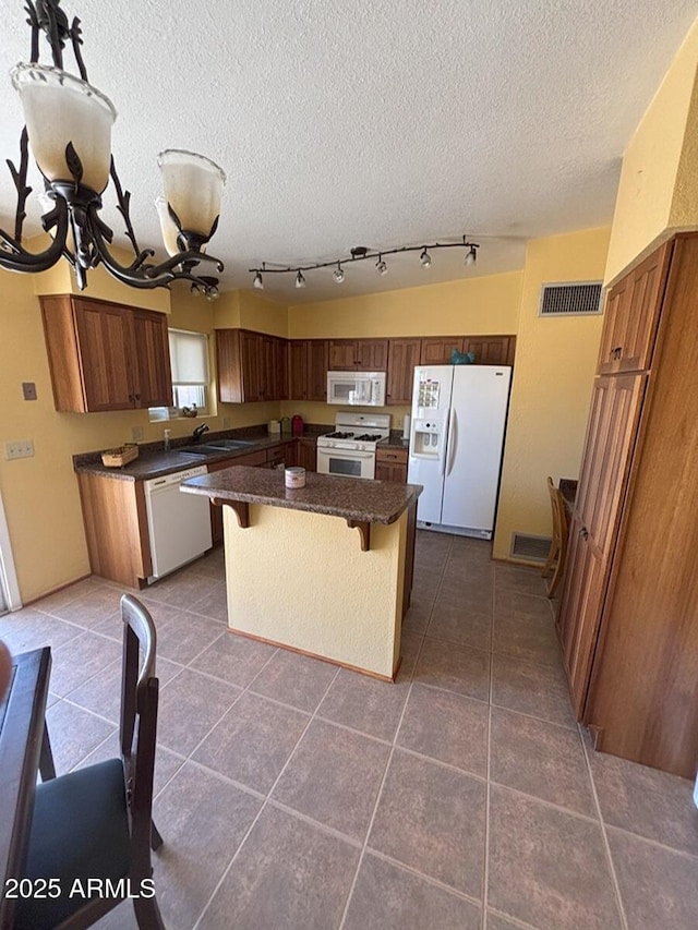 4910 E Foothills Dr, Sierra Vista, AZ 85635 - kitchen featuring white appliances, a textured ceiling, a kitchen bar, a center island, and dark tile patterned floors