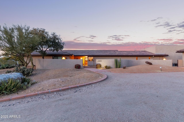 view of front of home with driveway, fence, a tiled roof, and stucco siding