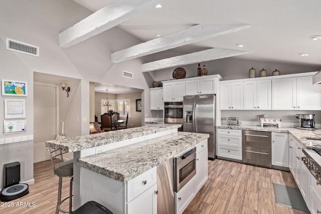 kitchen featuring visible vents, white cabinets, a center island, stainless steel appliances, and a warming drawer