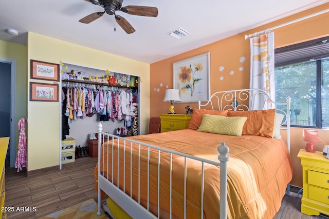 bedroom featuring dark wood-style floors, a closet, visible vents, and a ceiling fan