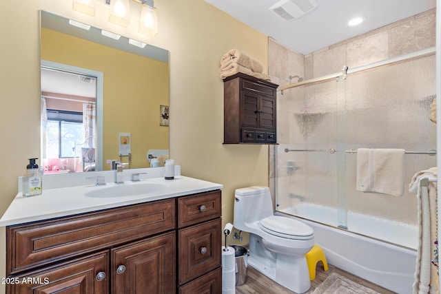 full bath featuring visible vents, bath / shower combo with glass door, toilet, wood finished floors, and vanity