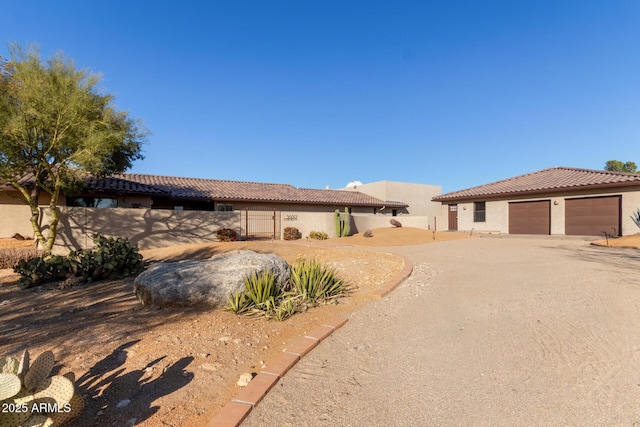 view of front of property with driveway, fence, a tiled roof, and stucco siding