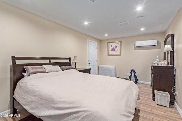 bedroom featuring light wood-style flooring, recessed lighting, visible vents, baseboards, and a wall mounted air conditioner