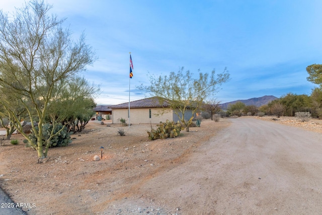 exterior space with a tiled roof, a mountain view, and stucco siding