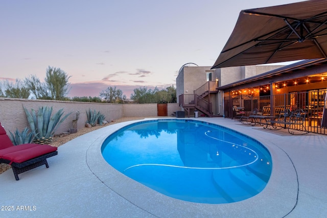 pool at dusk with a fenced in pool, a fenced backyard, a patio, and stairway