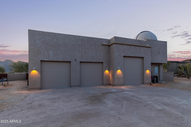 exterior space featuring driveway, an attached garage, and stucco siding