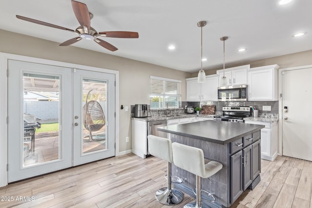 kitchen with french doors, white cabinetry, decorative light fixtures, a center island, and stainless steel appliances