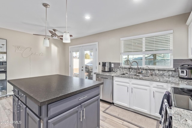 kitchen with pendant lighting, sink, light hardwood / wood-style flooring, stainless steel appliances, and white cabinets