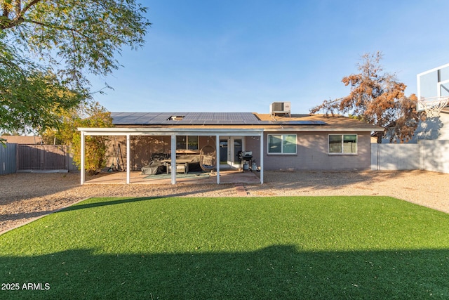 rear view of property with cooling unit, a patio area, solar panels, and a lawn