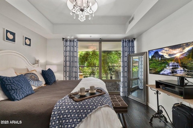 bedroom with a tray ceiling, an inviting chandelier, dark hardwood / wood-style flooring, and access to exterior